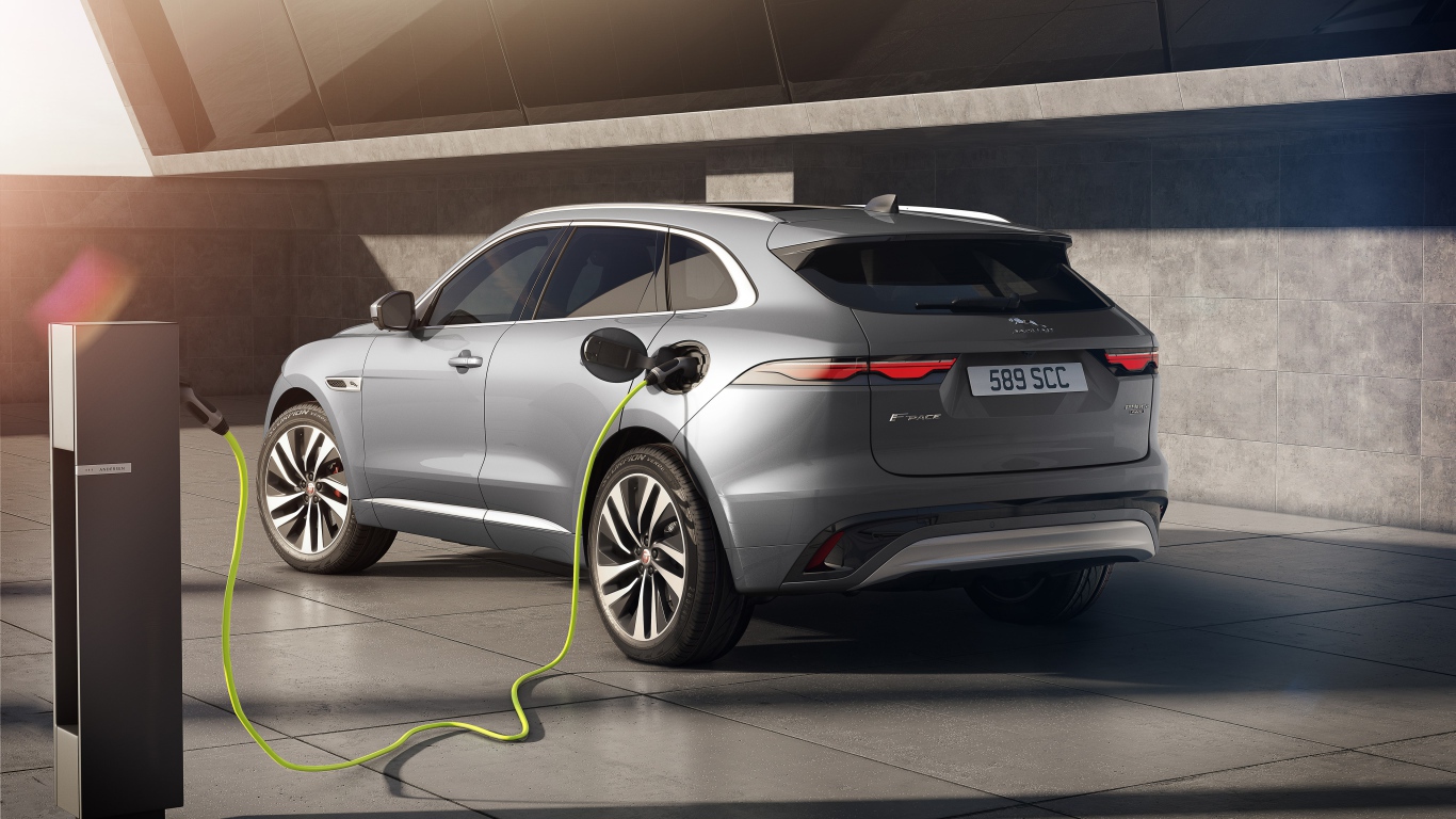 Серебристый автомобиль Jaguar F-Pace P400e AWD 2020 года на заправке 