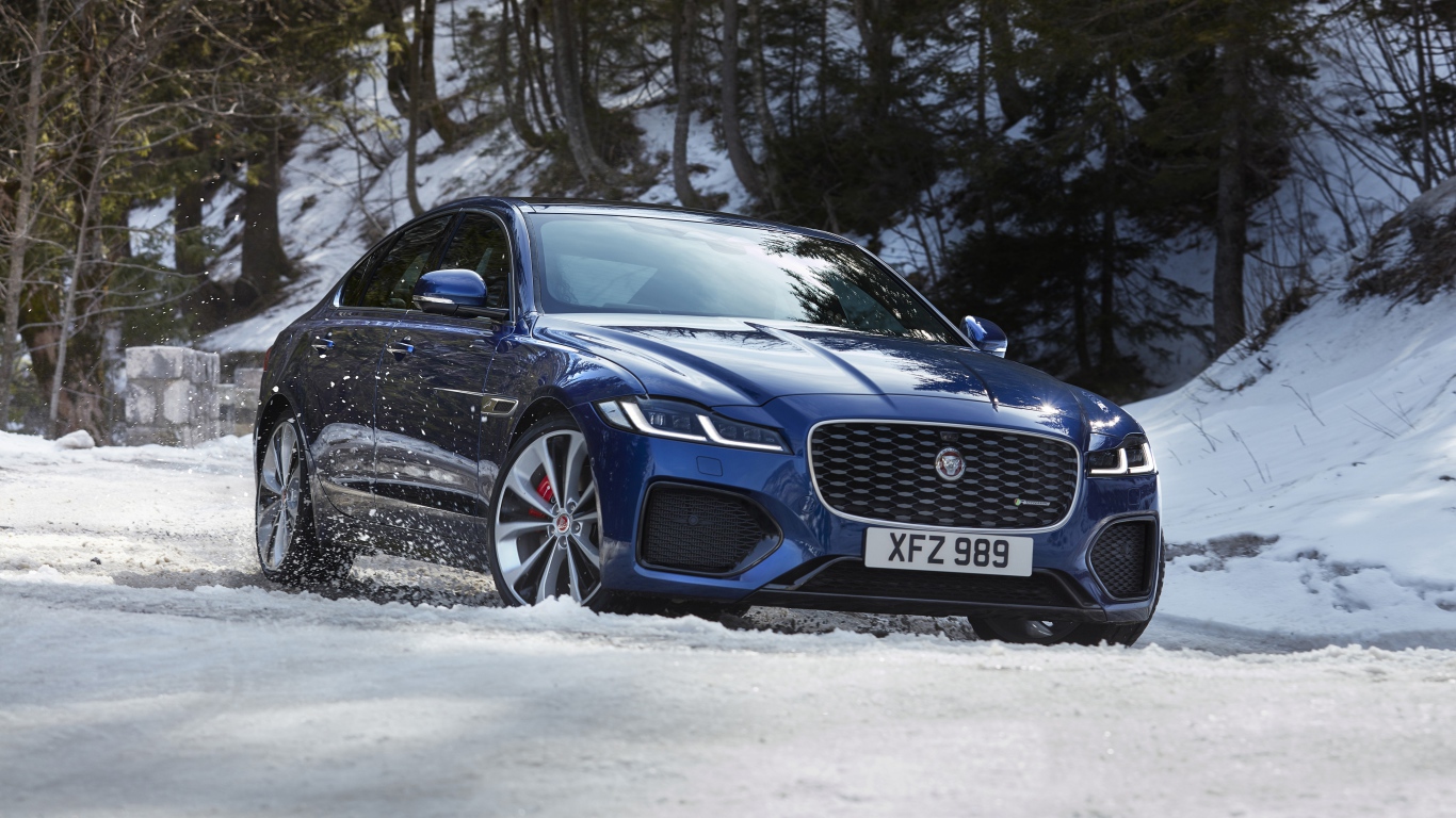 Синий Jaguar XF P300 AWD R-Dynamic 2020 года в заснеженном лесу 