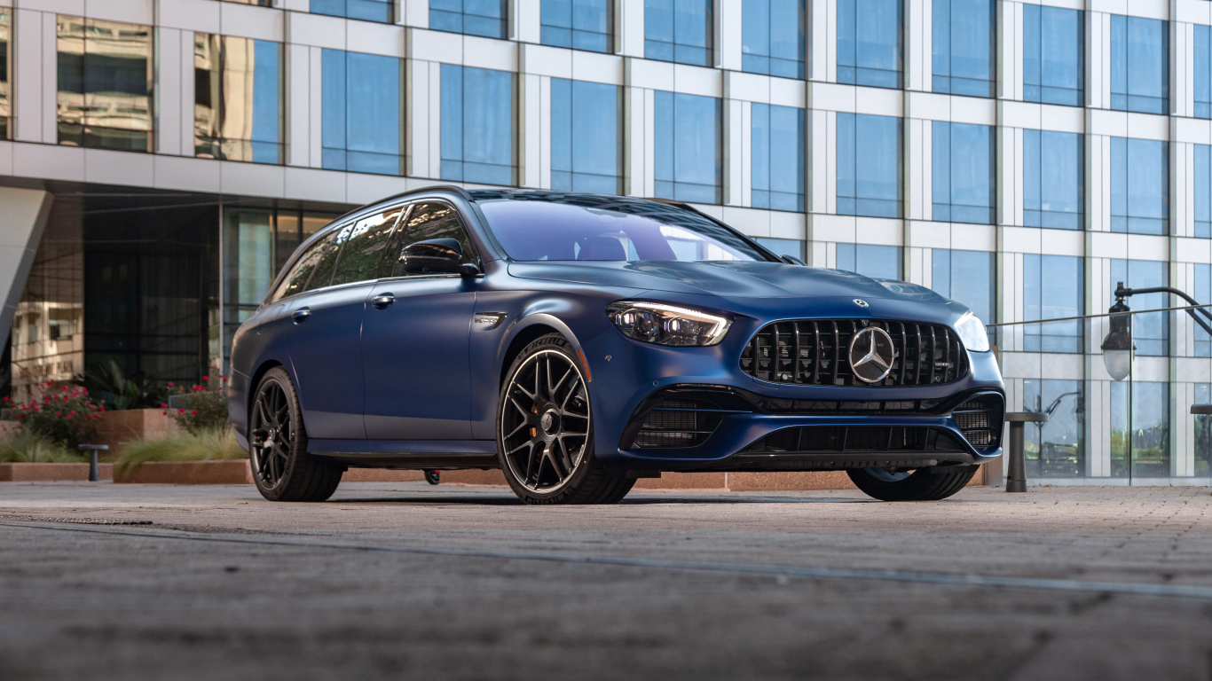 Синий автомобиль Mercedes-AMG E 63 S 4MATIC+, 2021 года на фоне дома