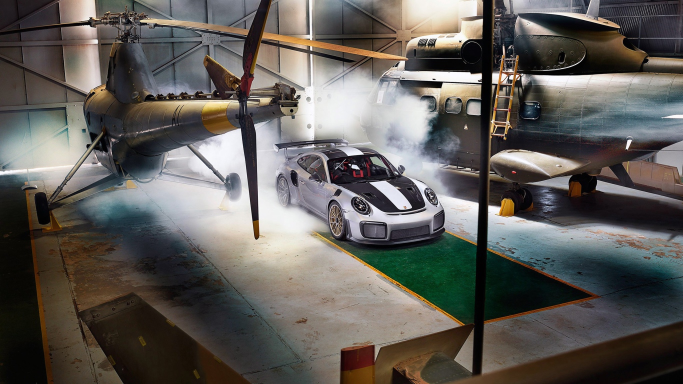 Автомобиль Porsche 911 GT2 RS в ангаре с вертолетами