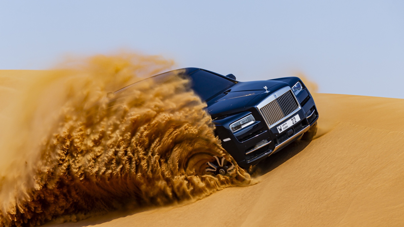 Черный Rolls-Royce Cullinan дрифтует по песку 