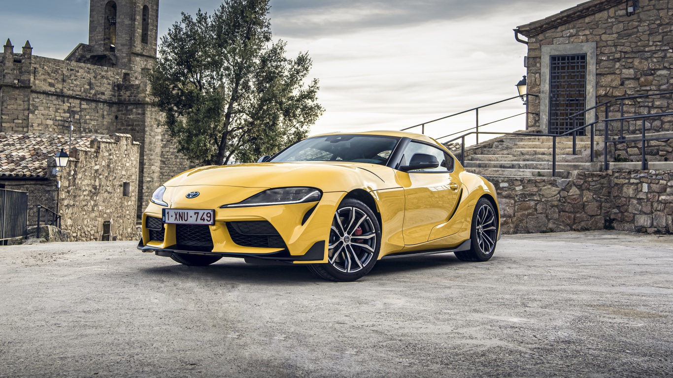 Желтый автомобиль Toyota GR Supra 2, 2020 года у старого здания 