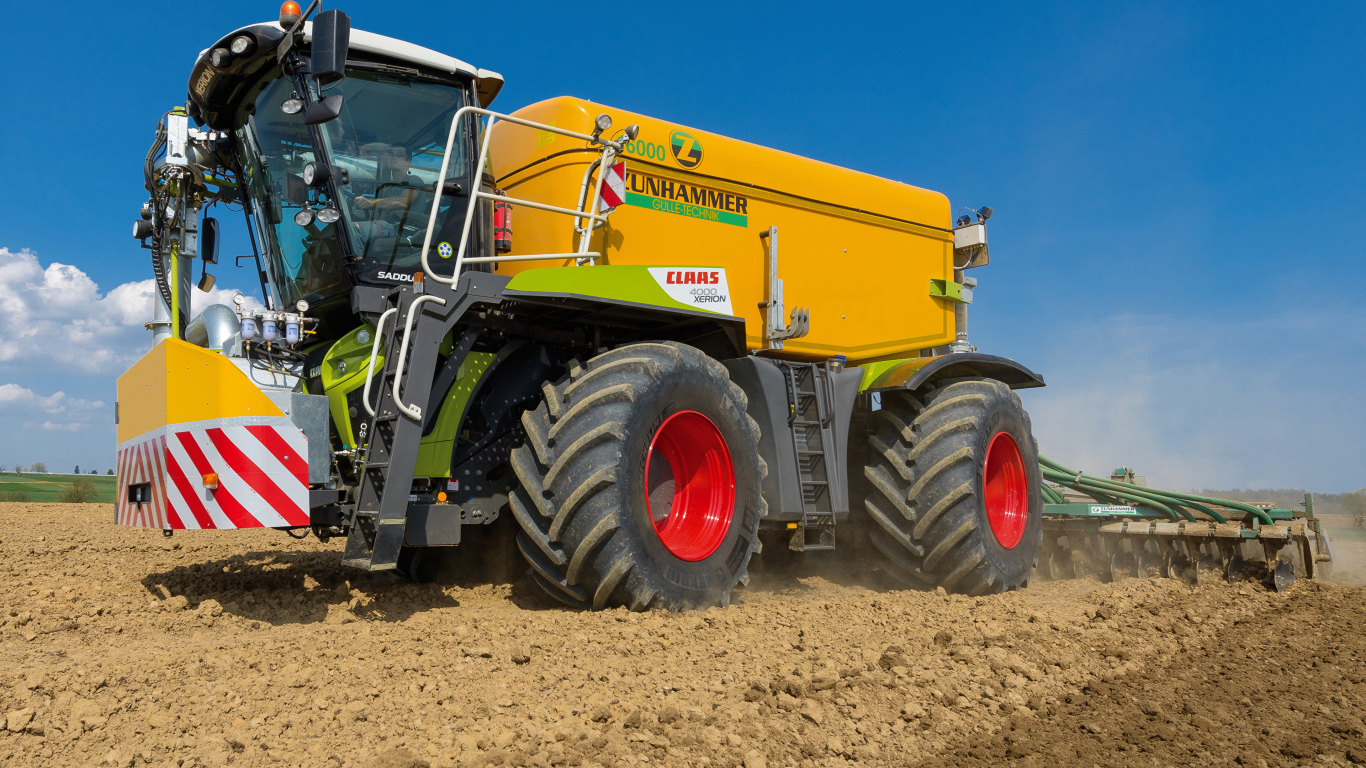 Большой комбайн пашет поле под голубым небом