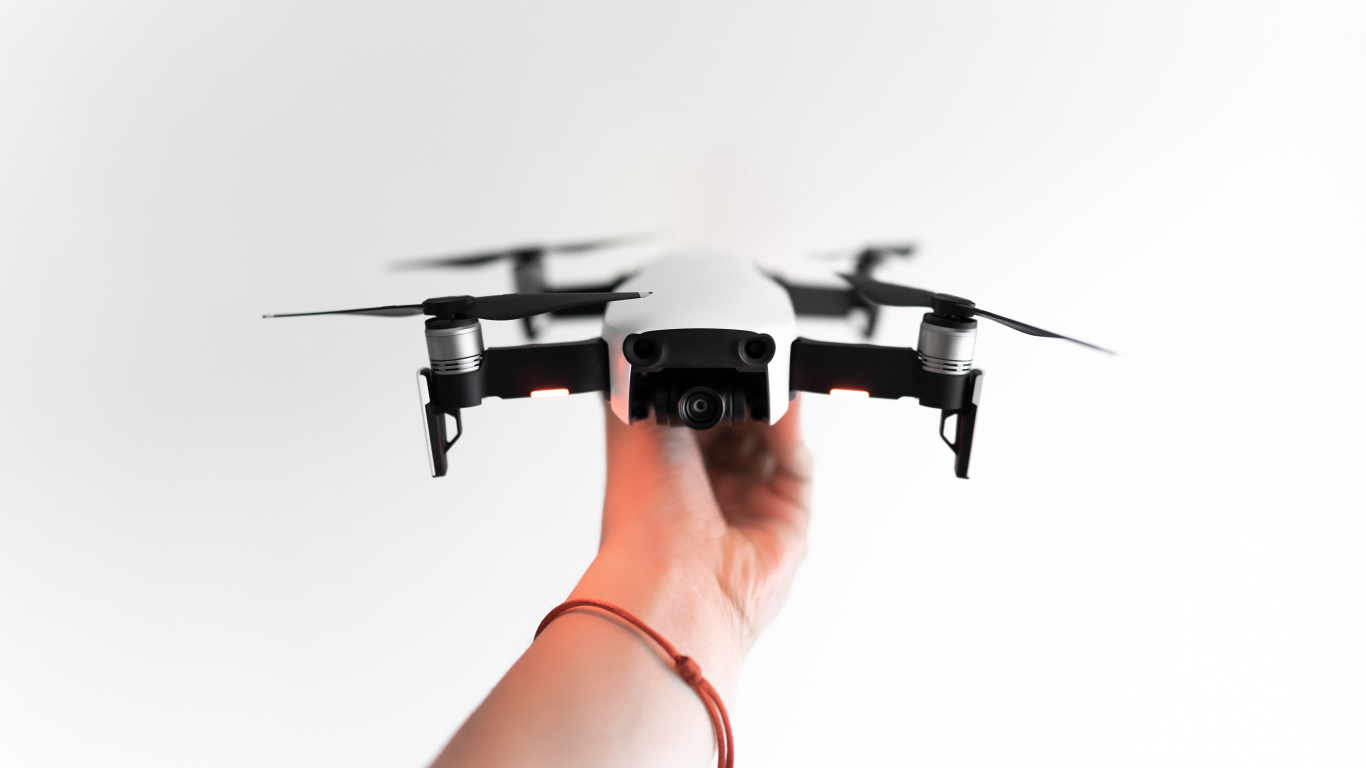 Белый квадрокоптер в руке на белом фоне