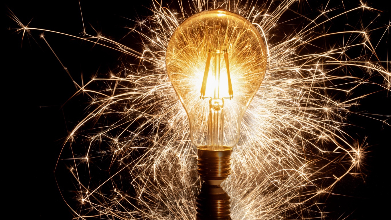 Зажженная лампа на черном фоне с искрами 
