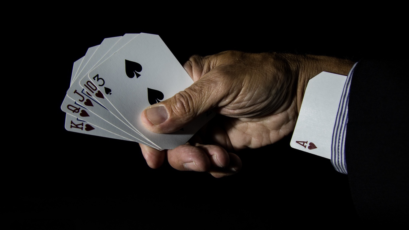 Туз в рукаве у шулера на черном фоне 