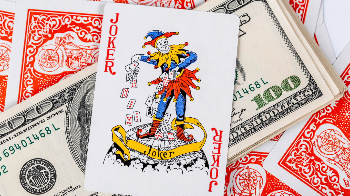 Карточный Джокер и пачка стодолларовых купюр