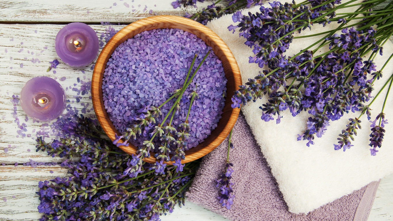 Ароматная соль, на столе с полотенцами, лавандой и зажженными свечами