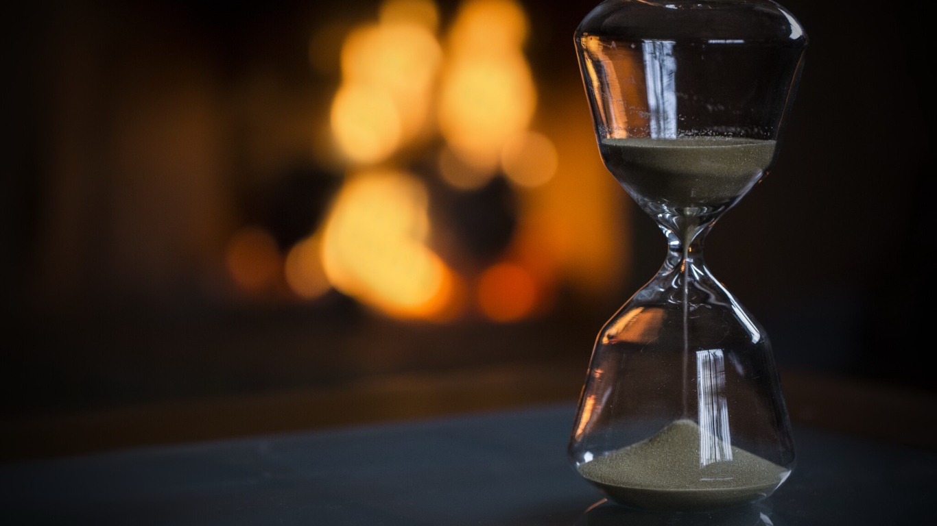 Стеклянные песочные часы на столе 