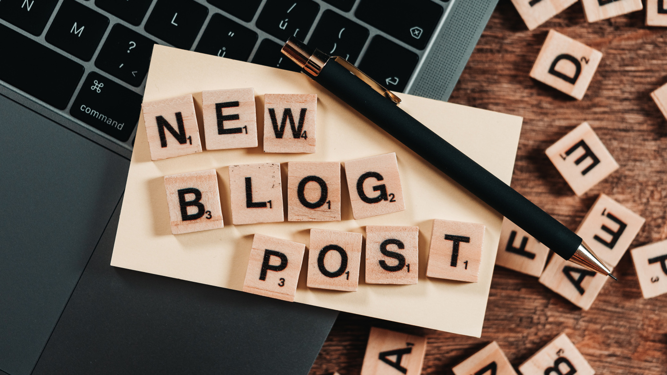 Надпись на английском New Blog Post возле ноутбука с ручкой 