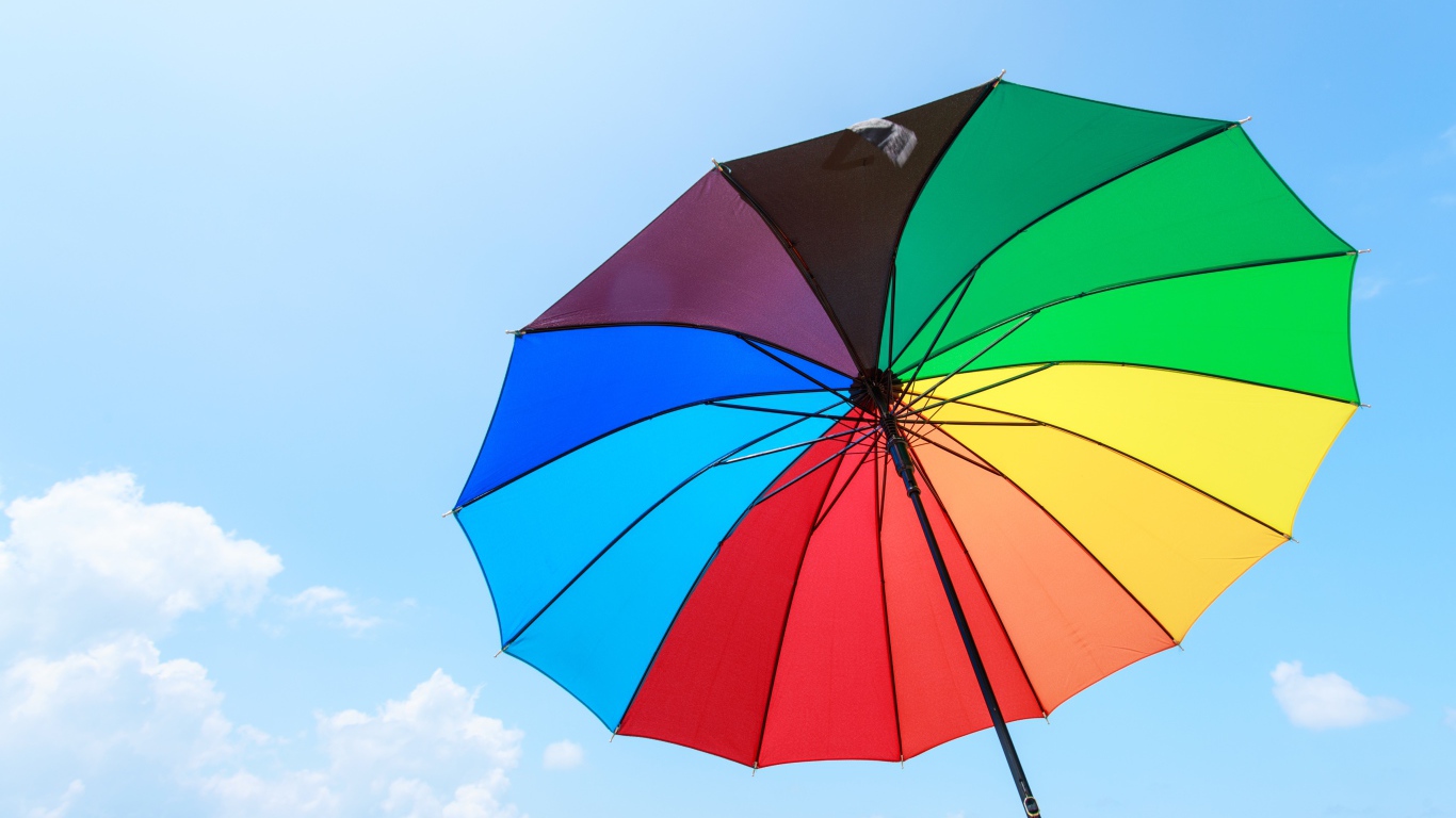Разноцветный зонт на фоне голубого неба 