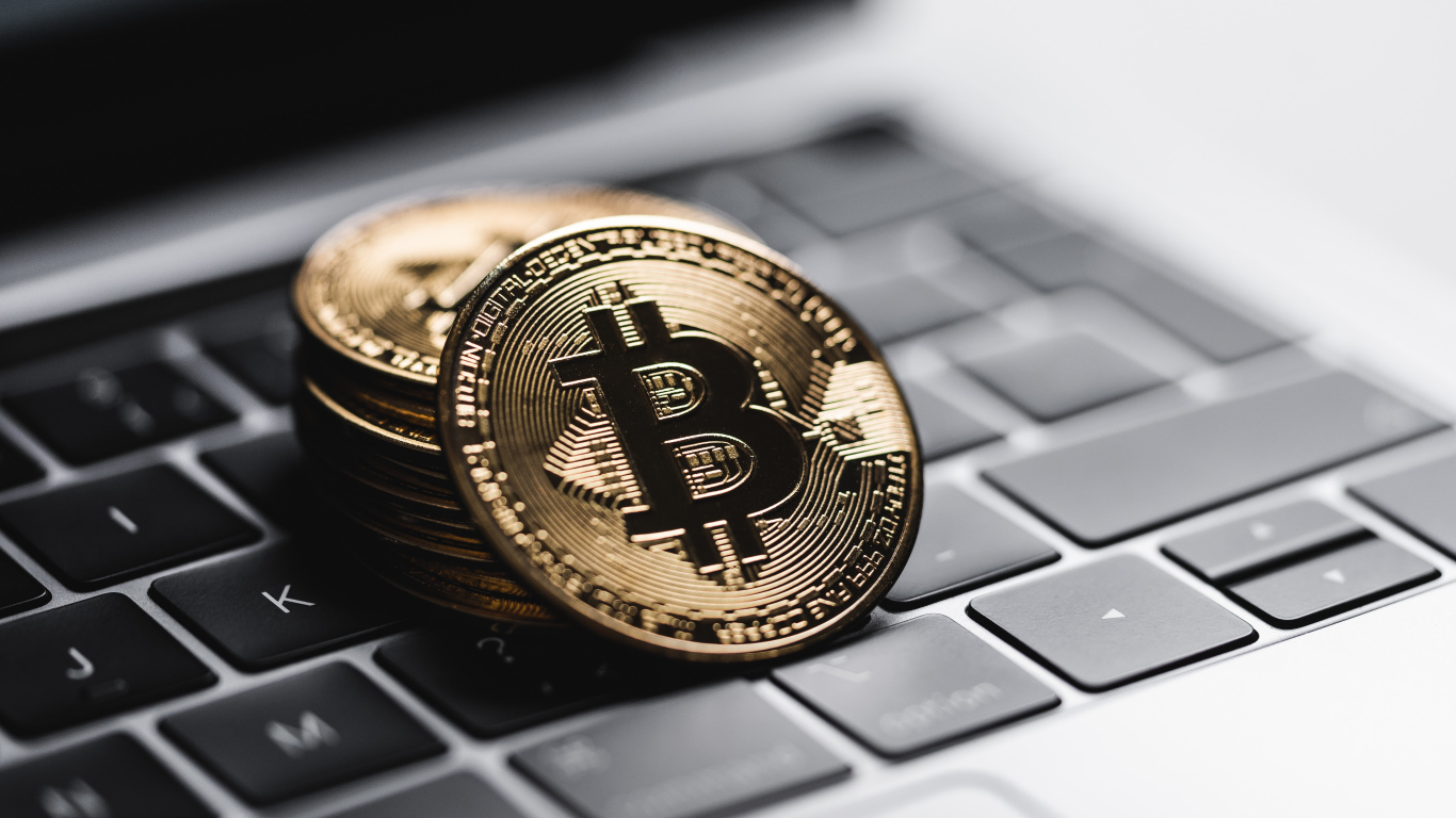 Монеты биткоин лежат на клавиатуре ноутбука 