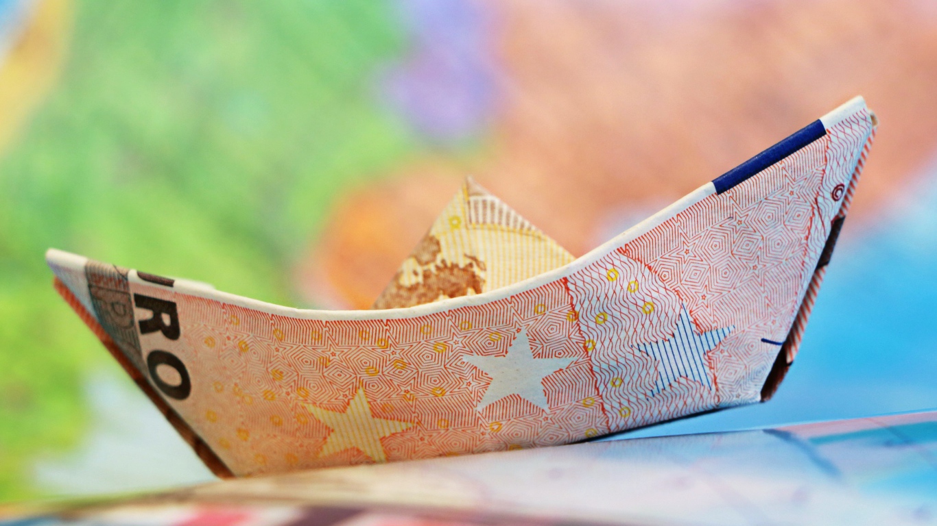 Кораблик из купюры евро на столе 