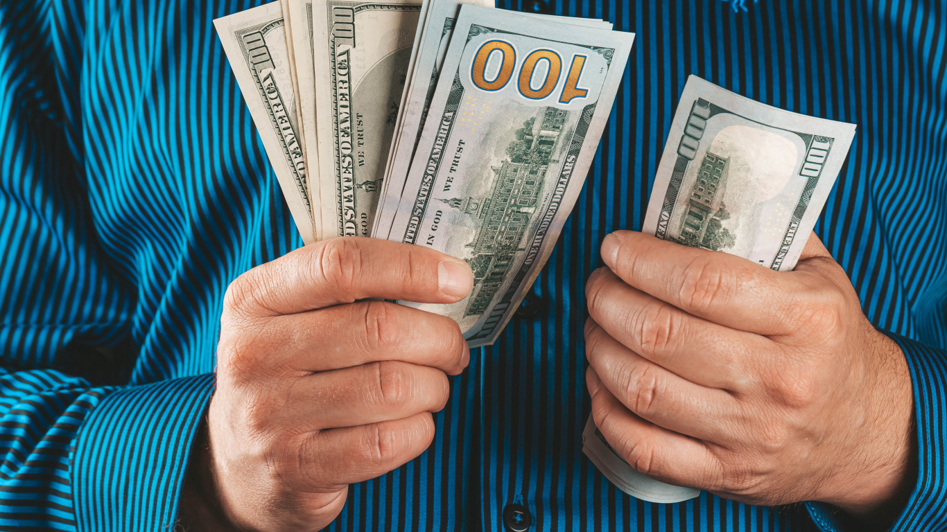 Мужчина считает сто долларовые купюры 