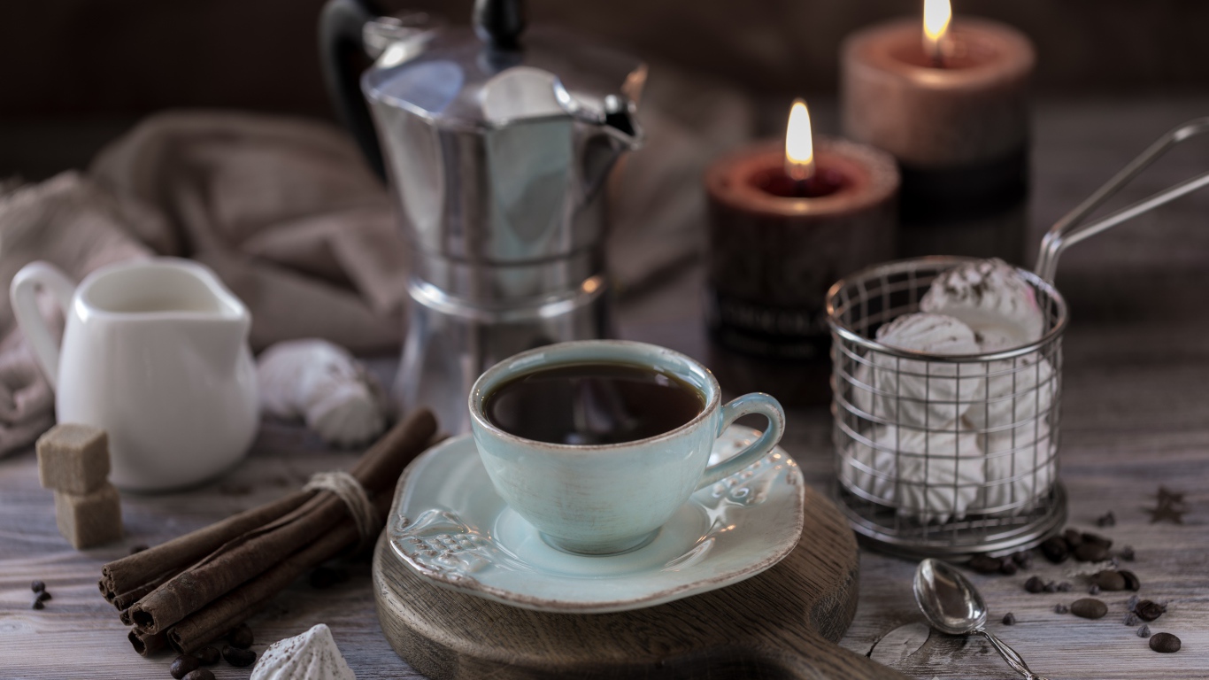 Чашка эспрессо на столе с корицей, зефиром и зажженными свечами