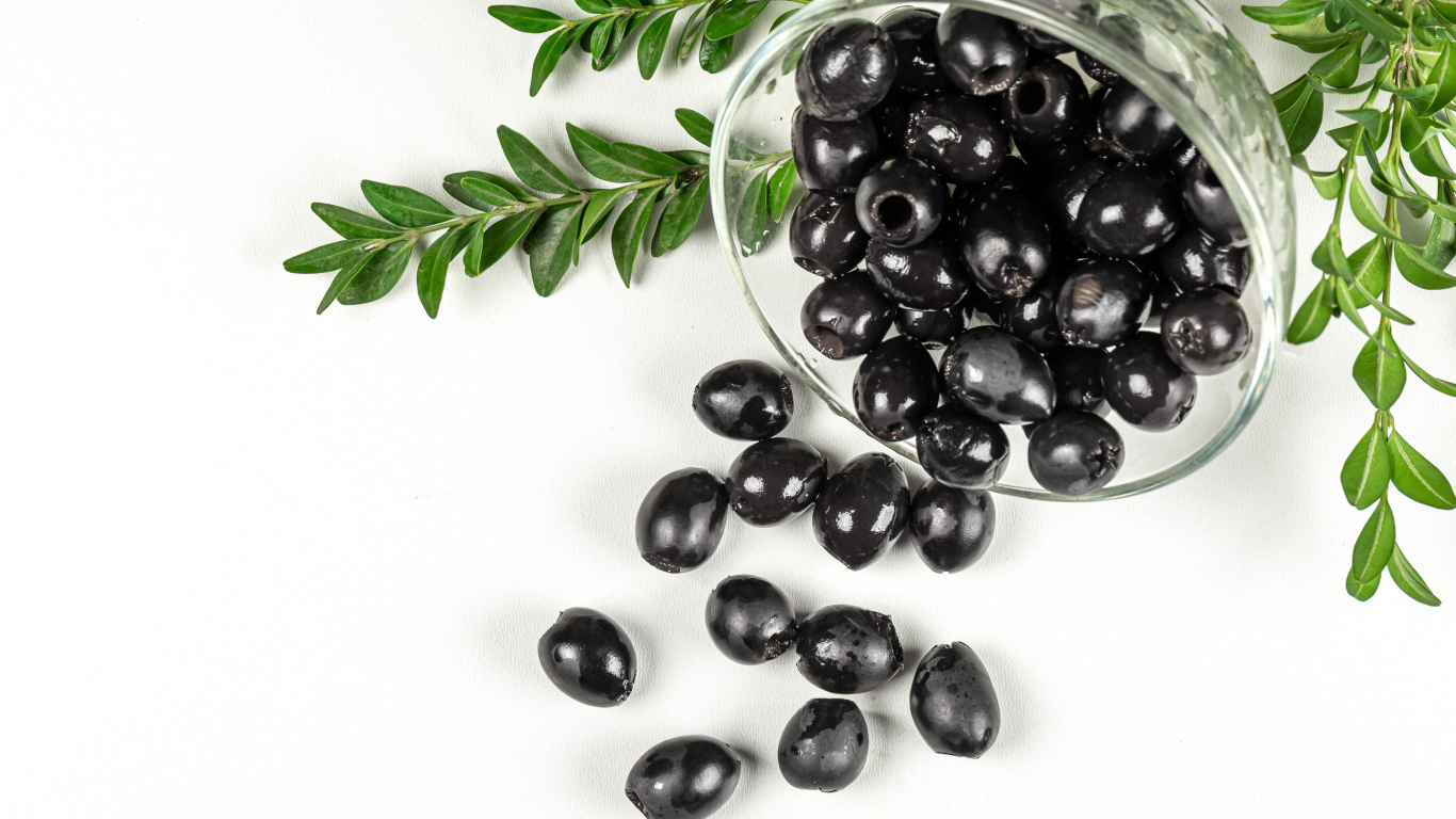Черные маслины с розмарином на белом фоне