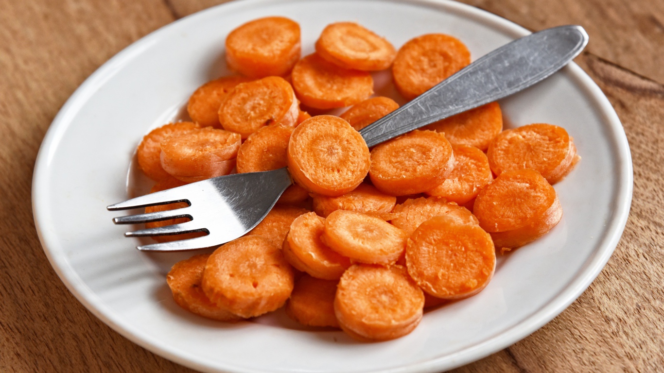 Carrot slices on a white plate with a fork