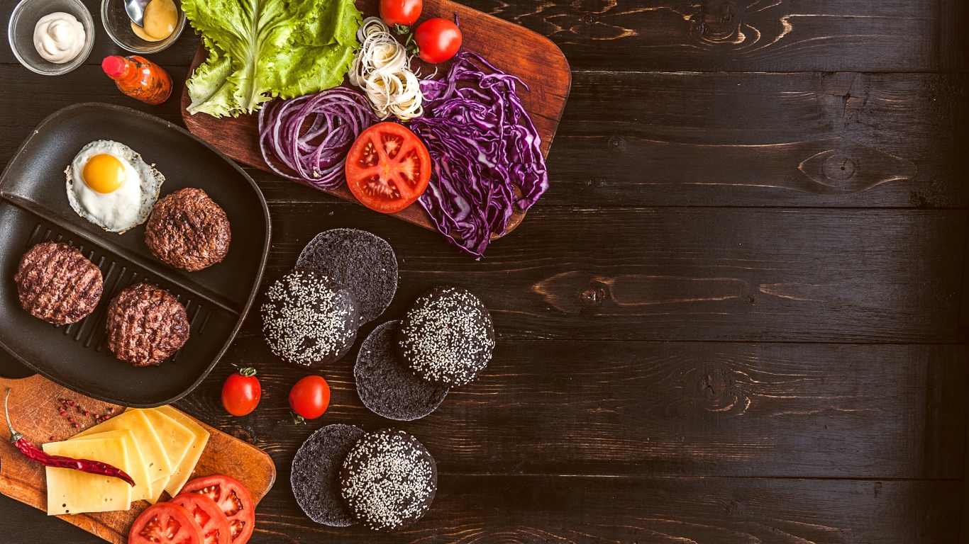 Повар готовит гамбургеры на деревянном столе