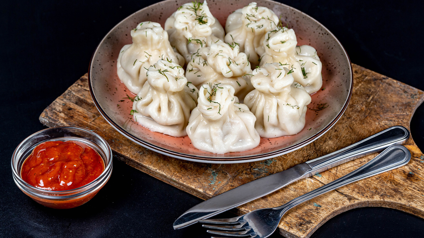 Вкусные горячие хинкали на столе с соусом
