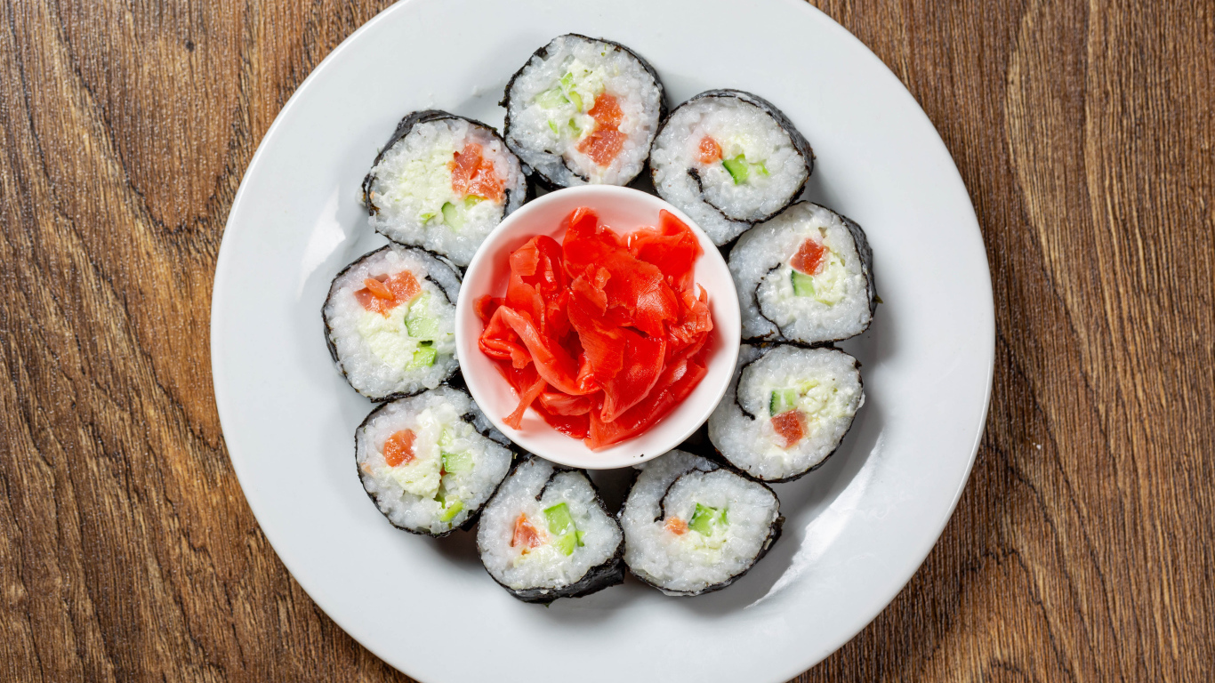 Вкусные суши на большой белой тарелке с имбирем