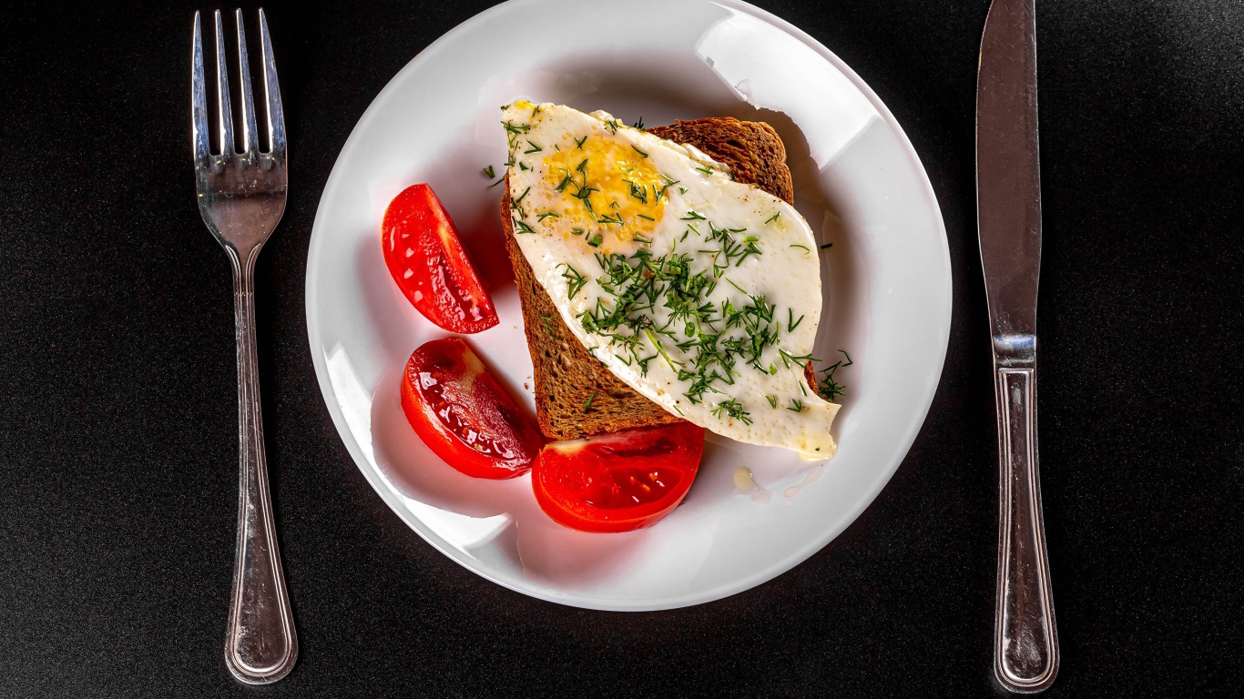 Бутерброд с яичницей на тарелке с помидорами