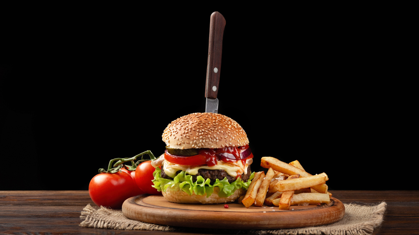 Гамбургер с ножом на столе с помидорами и картофелем фри 