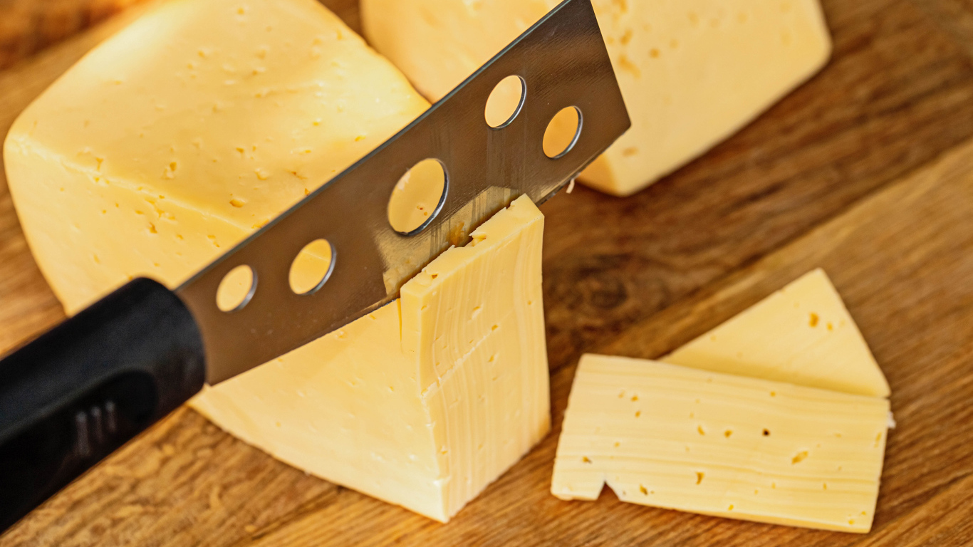 Твердый сыр с ножом на столе