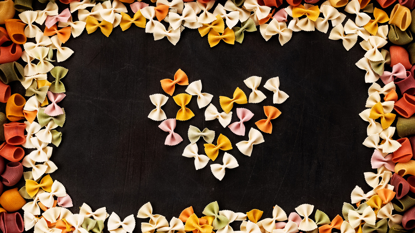 Сердце из разноцветных макарон на черном столе 