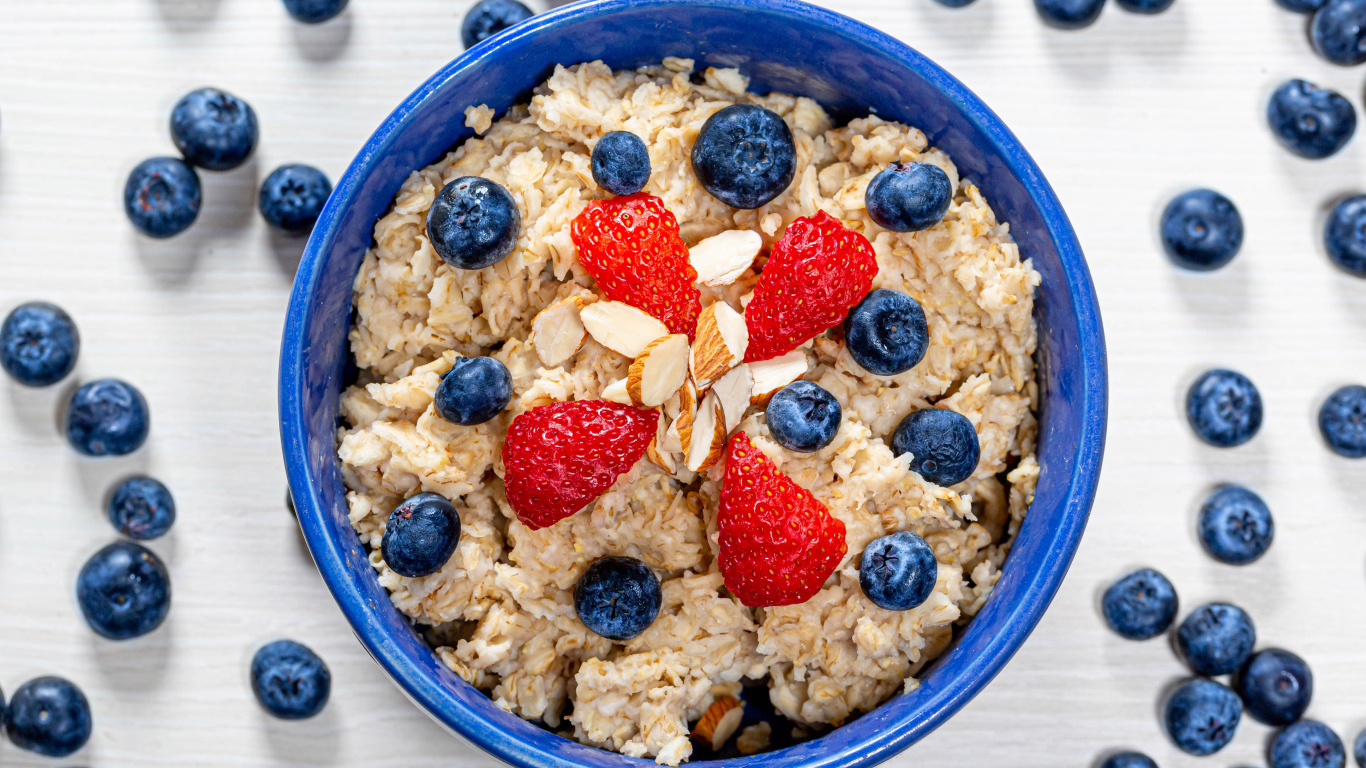 Овсяная каша в тарелке с ягодами черники и клубники 