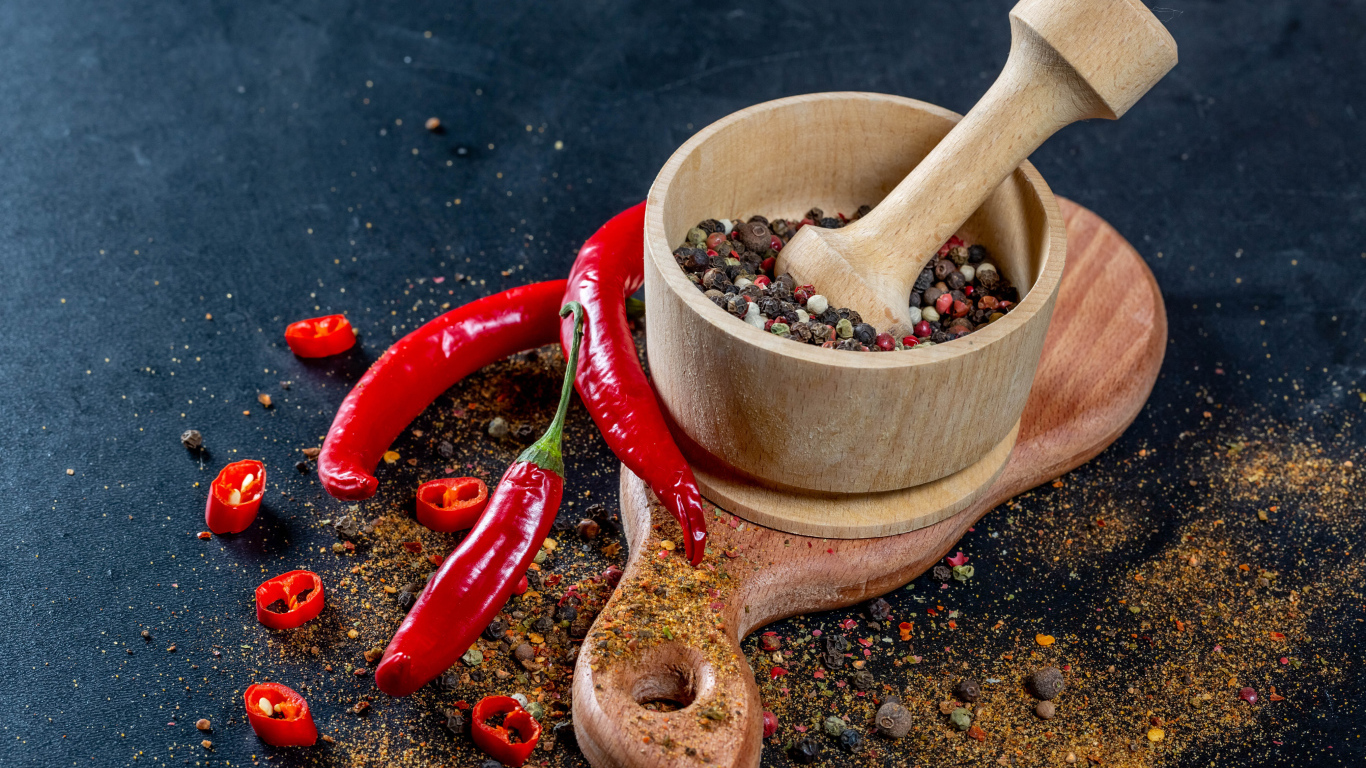 Peppercorns in a mortar on a table with hot pepper