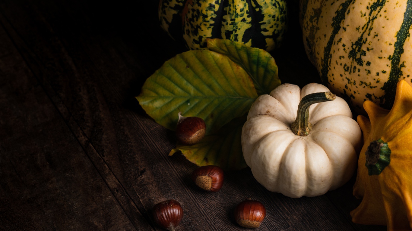 Тыква с каштанами на деревянном столе 