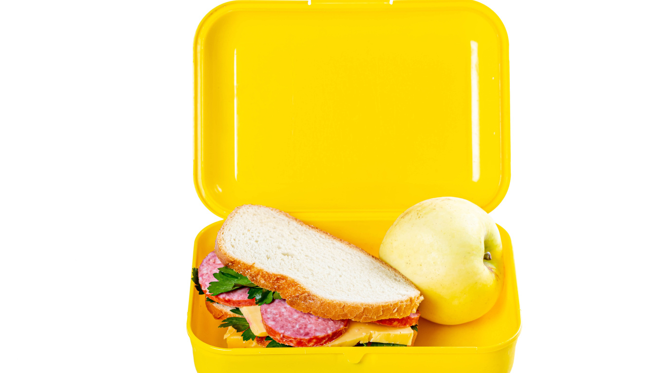 Бутерброд и яблоко в контейнере на белом фоне