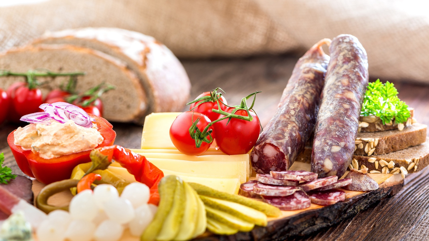 Колбаса на столе с огурцами, помидорами и перцем