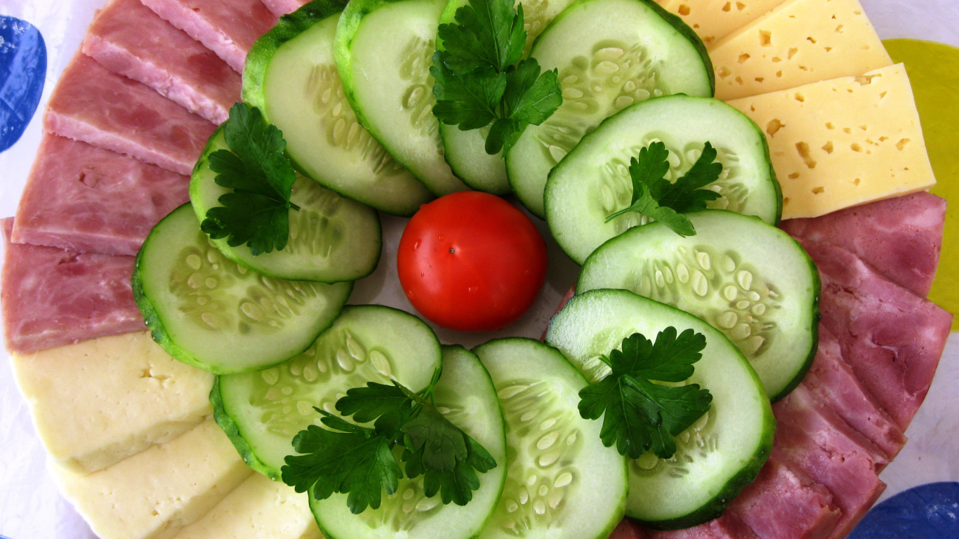 Сыр нарезанный, огурцы и ветчина на тарелке 