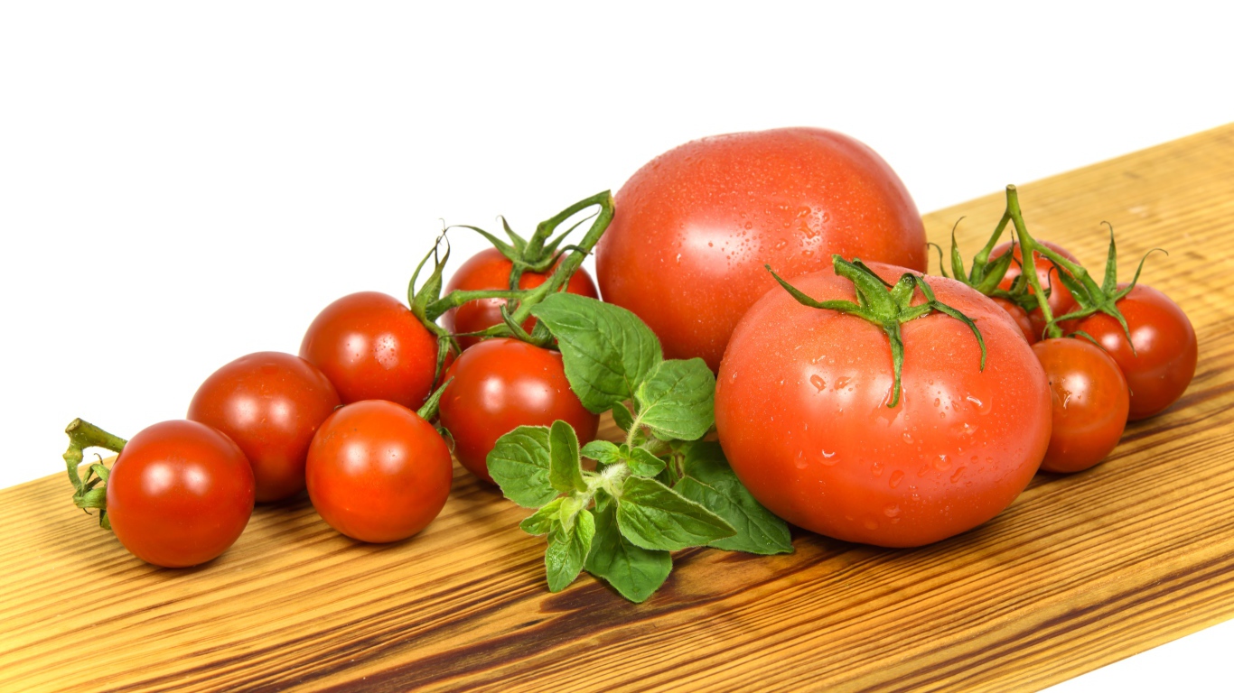 Маленькие и большие помидоры на деревянной доске 