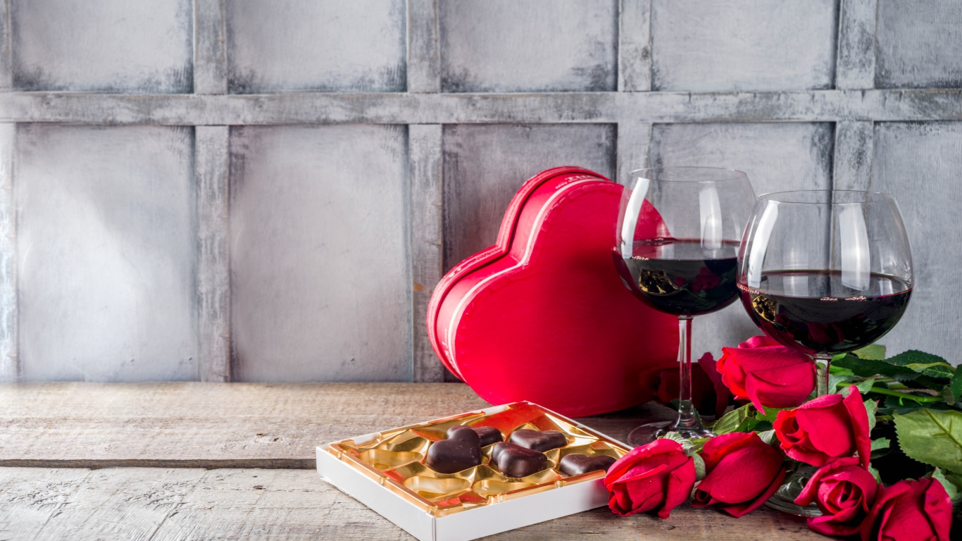 Два бокала вина, шоколадные конфеты и розы на столе для любимой 