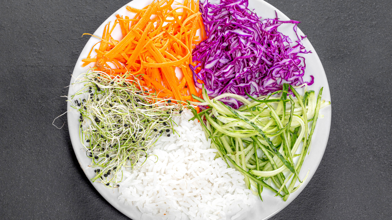 Овощи с рисом на большой  белой тарелке на сером столе 