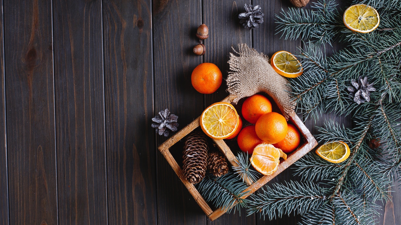 Ящик с мандаринами и шишками на столе с еловыми ветками