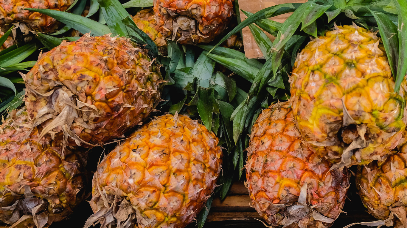 Много больших спелых ананасов на столе 