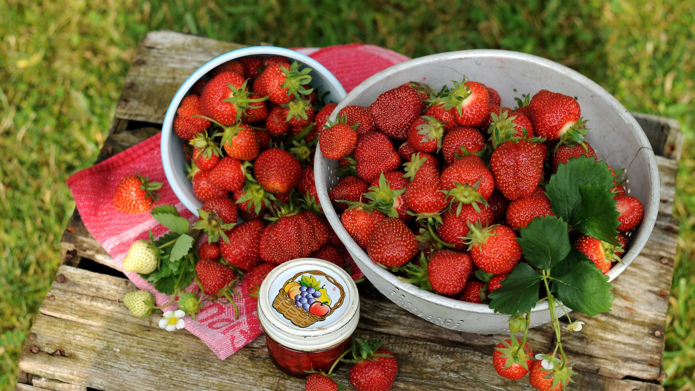 Много спелой ароматной клубники на столе с джемом 