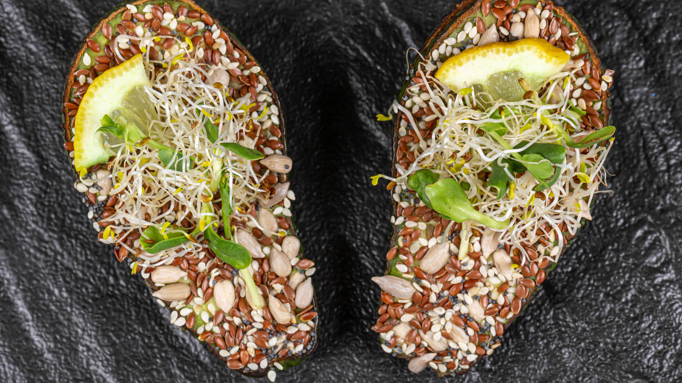 Половинки авокадо с проросшими зернами на столе