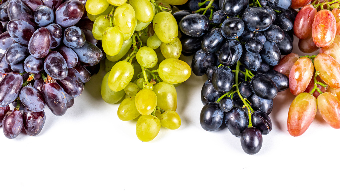 Грозди разноцветного винограда на белом фоне