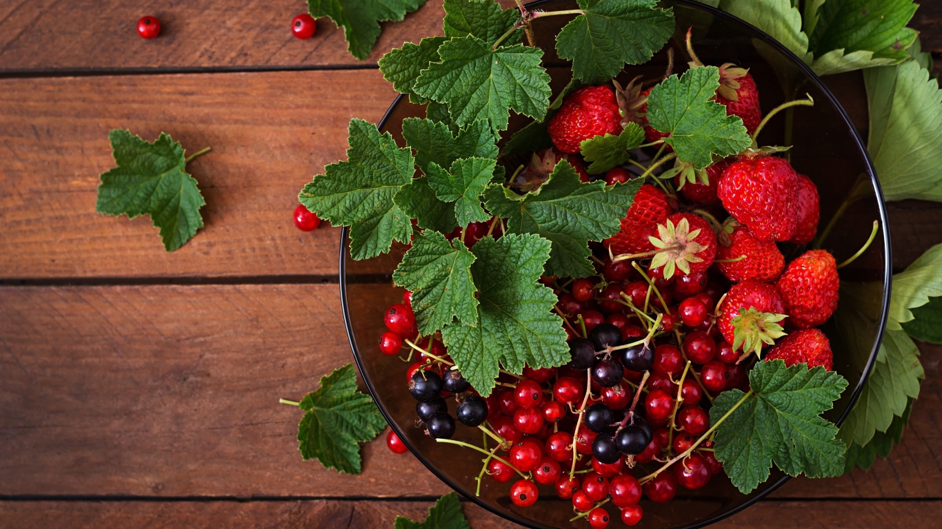 Ягоды смотродины в миске с клубникой и зелеными листьями