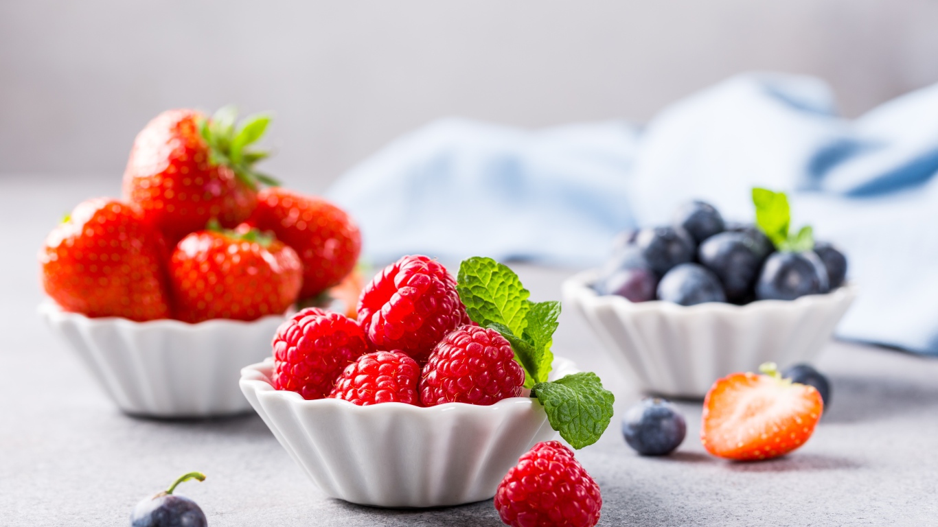 Свежие ягоды малины, клубники и черники на столе