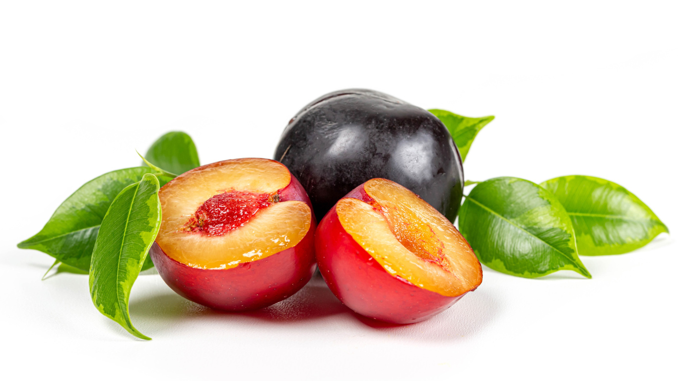 Сочные аппетитные сливы на белом фоне с зелеными листьями