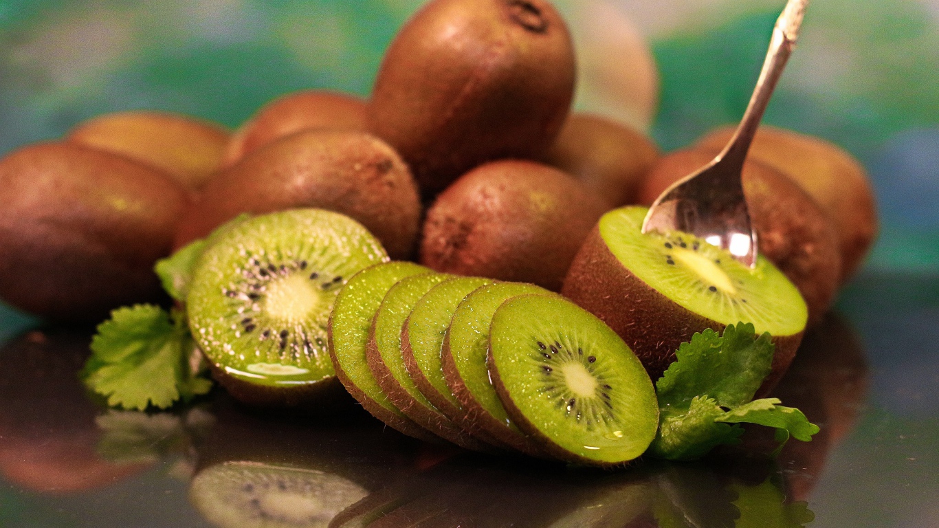 Много спелых плодов киви на столе с ложкой 