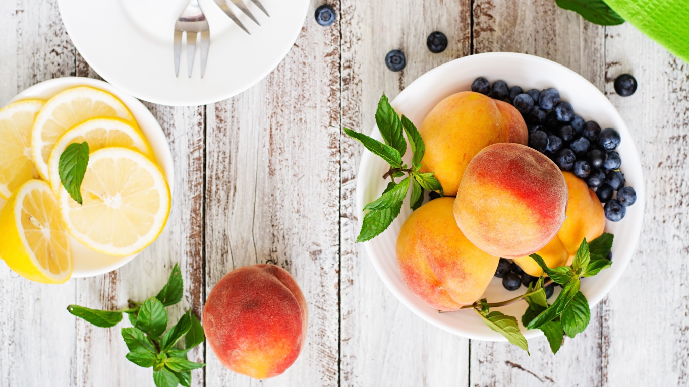 Персики на столе с лимоном и ягодами черники