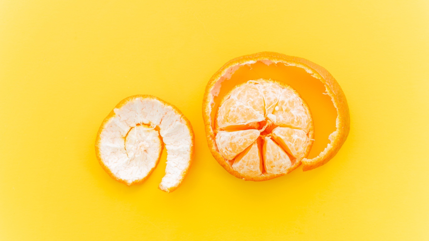 Peeled tangerine with peel on yellow background