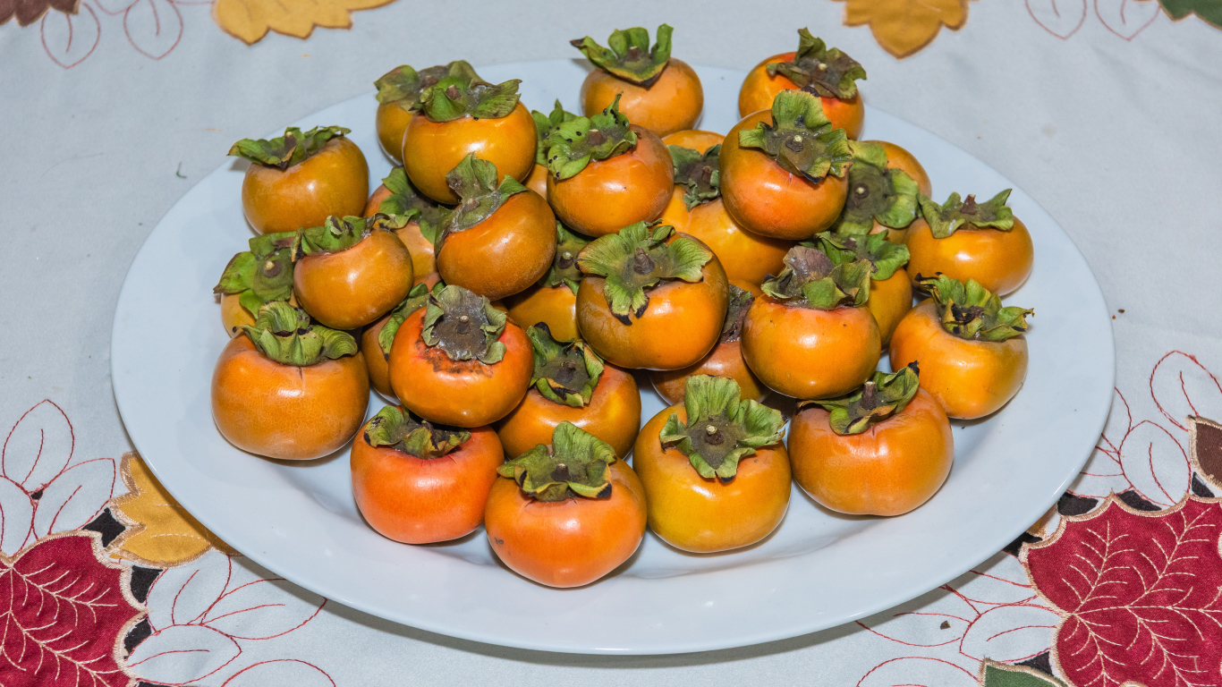 Спелый фрукт хурма на большой белой тарелке 