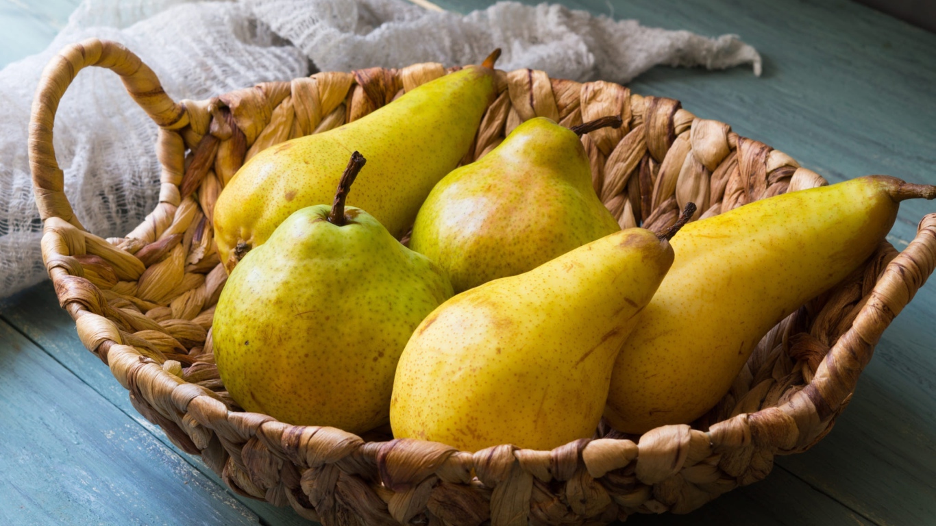 Спелые груши лежат в корзине на столе